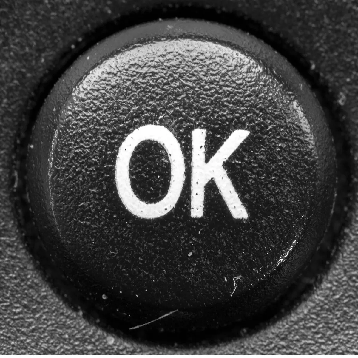 Macro photograph of the "OK" button on a TV remote control